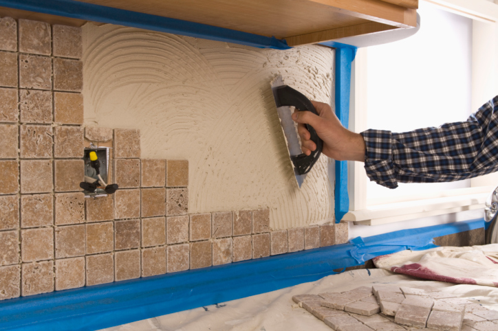 man putting tile on wall